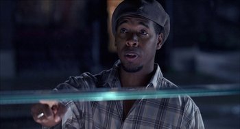 Movie still from “Barbershop 2: Back in Business” (2004), directed by Kevin Rodney Sullivan – A man in a plaid shirt holding a green object; Close Up shot, Over the shoulder angle