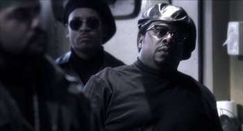 Movie still from “Barbershop 2: Back in Business” (2004), directed by Kevin Rodney Sullivan – A man in a black shirt and a man in a silver hat and sunglasses; Close Up shot, Low angle