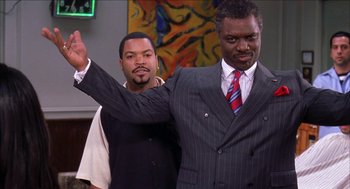 Movie still from “Barbershop 2: Back in Business” (2004), directed by Kevin Rodney Sullivan – Two men in suits and one is holding up his hand; Medium shot, Over the shoulder angle