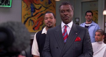 Movie still from “Barbershop 2: Back in Business” (2004), directed by Kevin Rodney Sullivan – A man in a suit standing next to another man in a tie; Medium shot, Over the shoulder angle