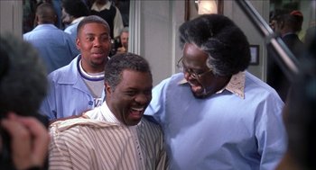 Movie still from “Barbershop 2: Back in Business” (2004), directed by Kevin Rodney Sullivan – A group of men standing next to each other in a room; Medium shot, Over the shoulder angle