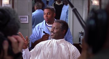 Movie still from “Barbershop 2: Back in Business” (2004), directed by Kevin Rodney Sullivan – A man getting his hair cut by another man; Medium shot, Over the shoulder angle