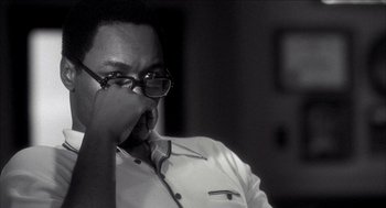 Movie still from “Barbershop 2: Back in Business” (2004), directed by Kevin Rodney Sullivan – A black and white photo of a man wearing glasses; Close Up shot, Over the shoulder angle