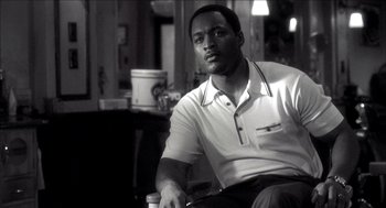 Movie still from “Barbershop 2: Back in Business” (2004), directed by Kevin Rodney Sullivan – A black and white photo of a man sitting in a chair; Close Up shot, Low angle