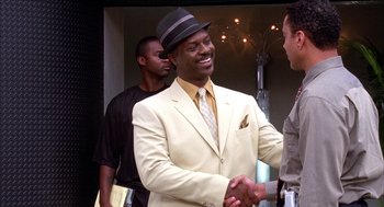 Movie still from “Barbershop 2: Back in Business” (2004), directed by Kevin Rodney Sullivan – A man in a suit shaking hands with another man in a suit; Medium shot, Over the shoulder angle