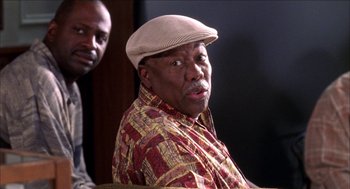 Movie still from “Barbershop 2: Back in Business” (2004), directed by Kevin Rodney Sullivan – An older man wearing a hat and a colorful shirt; Close Up shot, Over the shoulder angle