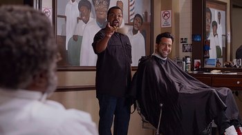 Movie still from “Barbershop: The Next Cut” (2016), directed by Malcolm D. Lee – Two men in a barber shop one is holding a brush and the other is sitting in a barber chair; Medium shot, Over the shoulder angle