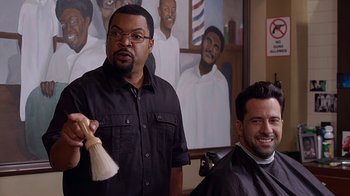 Movie still from “Barbershop: The Next Cut” (2016), directed by Malcolm D. Lee – Two men sitting in front of a painting of a barber shop; Medium shot, Over the shoulder angle