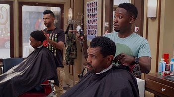Movie still from “Barbershop: The Next Cut” (2016), directed by Malcolm D. Lee – A man getting his hair cut by another man; Medium shot, Over the shoulder angle