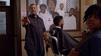 Movie still from “Barbershop: The Next Cut” (2016), directed by Malcolm D. Lee – A man is getting his hair cut by another man; Medium shot, Over the shoulder angle