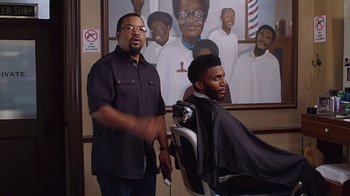 Movie still from “Barbershop: The Next Cut” (2016), directed by Malcolm D. Lee – A man getting his hair cut by another man; Medium shot, Over the shoulder angle