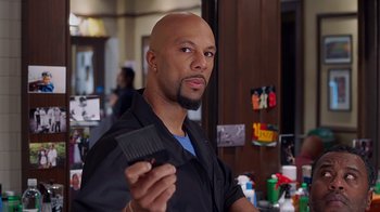 Movie still from “Barbershop: The Next Cut” (2016), directed by Malcolm D. Lee – A bald man holding a comb in a barber shop; Close Up shot, Over the shoulder angle
