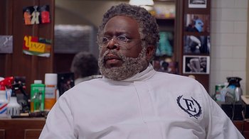 Movie still from “Barbershop: The Next Cut” (2016), directed by Malcolm D. Lee – A man with a beard and glasses is wearing a chef's outfit; Close Up shot, Over the shoulder angle