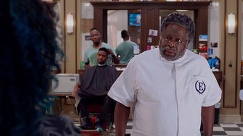 Movie still from “Barbershop: The Next Cut” (2016), directed by Malcolm D. Lee – A man standing in front of a mirror in a barber shop; Medium shot, Over the shoulder angle