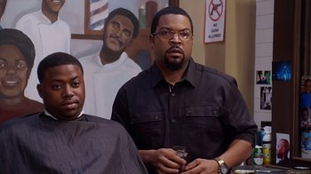Movie still from “Barbershop: The Next Cut” (2016), directed by Malcolm D. Lee – Two men are standing in front of a painting; Medium shot, Over the shoulder angle