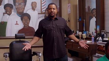 Movie still from “Barbershop: The Next Cut” (2016), directed by Malcolm D. Lee – A man standing in front of a painting of a barber shop; Medium shot, Over the shoulder angle