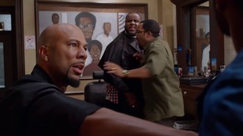 Movie still from “Barbershop: The Next Cut” (2016), directed by Malcolm D. Lee – A man getting his hair cut at a barber shop; Medium shot, Over the shoulder angle