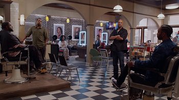 Movie still from “Barbershop: The Next Cut” (2016), directed by Malcolm D. Lee – A group of people sitting in a room with chairs; Wide shot, Over the shoulder angle