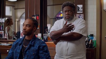 Movie still from “Barbershop: The Next Cut” (2016), directed by Malcolm D. Lee – A man standing next to another man in front of a mirror; Medium shot, Over the shoulder angle