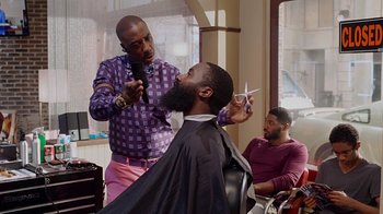 Movie still from “Barbershop: The Next Cut” (2016), directed by Malcolm D. Lee – A man getting his hair cut at a barber shop; Medium shot, Over the shoulder angle
