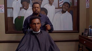 Movie still from “Barbershop: The Next Cut” (2016), directed by Malcolm D. Lee – A man getting his hair cut by another man; Medium shot, Over the shoulder angle