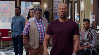 Movie still from “Barbershop: The Next Cut” (2016), directed by Malcolm D. Lee – A group of people standing next to each other in front of a building; Medium shot, Over the shoulder angle
