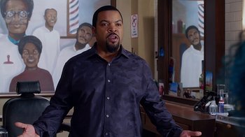 Movie still from “Barbershop: The Next Cut” (2016), directed by Malcolm D. Lee – Ice cube in front of a painting of a barber shop; Medium shot, Over the shoulder angle