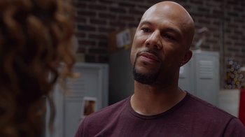 Movie still from “Barbershop: The Next Cut” (2016), directed by Malcolm D. Lee – A man with a beard and a purple t - shirt; Close Up shot, Over the shoulder angle