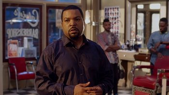 Movie still from “Barbershop: The Next Cut” (2016), directed by Malcolm D. Lee – A man standing in front of another man in front of a mirror; Medium shot, Over the shoulder angle