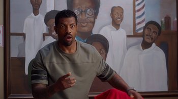 Movie still from “Barbershop: The Next Cut” (2016), directed by Malcolm D. Lee – A man standing in front of a painting of a man; Medium shot, Over the shoulder angle