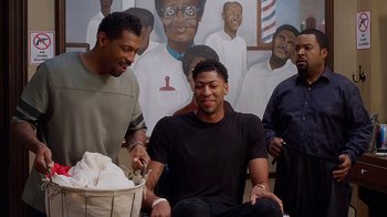 Movie still from “Barbershop: The Next Cut” (2016), directed by Malcolm D. Lee – A man sitting in front of a painting of a barber shop; Medium shot, Over the shoulder angle