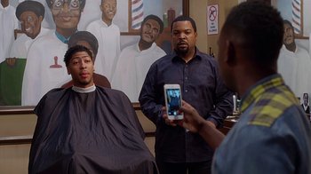Movie still from “Barbershop: The Next Cut” (2016), directed by Malcolm D. Lee – Two men in a barber shop one of which is taking a picture of the other; Medium shot, Over the shoulder angle