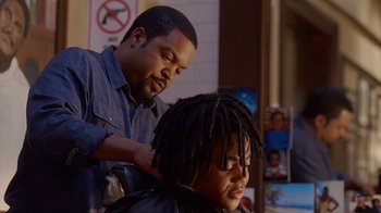 Movie still from “Barbershop: The Next Cut” (2016), directed by Malcolm D. Lee – A man cutting a child's dreadlocks in a barber shop; Close Up shot, Over the shoulder angle