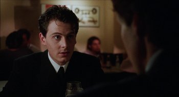 Movie still from “Barcelona” (1994), directed by Whit Stillman – A man in a suit and tie sitting at a table; Close Up shot, Over the shoulder angle
