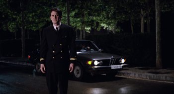 Movie still from “Barcelona” (1994), directed by Whit Stillman – A man standing in front of a car at night; Medium shot, Low angle