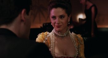 Movie still from “Barcelona” (1994), directed by Whit Stillman – A woman in a yellow and white dress with pearls around her neck; Close Up shot, Over the shoulder angle