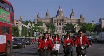 Movie still from “Barcelona” (1994), directed by Whit Stillman – A group of people on motor scooters on a city street; Extreme Wide shot, Low angle