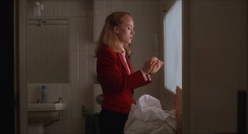 Movie still from “Barcelona” (1994), directed by Whit Stillman – A woman standing in a bathroom next to a window; Medium shot, Low angle