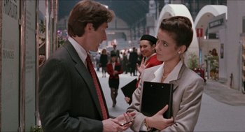 Movie still from “Barcelona” (1994), directed by Whit Stillman – A man and a woman in business attire talking to each other; Medium shot, Over the shoulder angle
