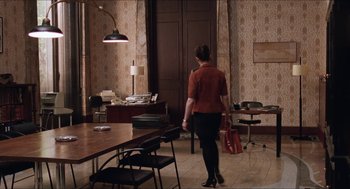 Movie still from “Barcelona” (1994), directed by Whit Stillman – A woman in a red shirt is walking in a room; Wide shot, Over the shoulder angle