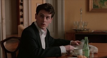 Movie still from “Barcelona” (1994), directed by Whit Stillman – A young man sitting at a table with a cup of coffee; Close Up shot, Over the shoulder angle