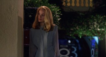 Movie still from “Barcelona” (1994), directed by Whit Stillman – A woman standing in front of a tree at night; Medium shot, Over the shoulder angle