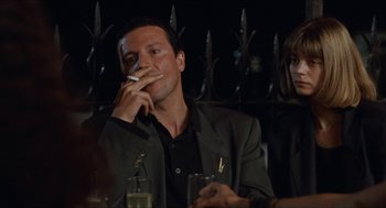 Movie still from “Barcelona” (1994), directed by Whit Stillman – A man sitting at a table with a cigarette in his mouth; Close Up shot, Over the shoulder angle