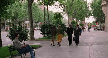 Movie still from “Barcelona” (1994), directed by Whit Stillman – A group of people walking down a sidewalk near trees; Wide shot, Over the shoulder angle