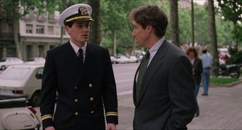 Movie still from “Barcelona” (1994), directed by Whit Stillman – A man in a suit talks to a man in a uniform; Medium shot, Over the shoulder angle