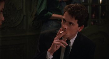 Movie still from “Barcelona” (1994), directed by Whit Stillman – A man in a suit and tie eating a piece of pizza; Close Up shot, Low angle