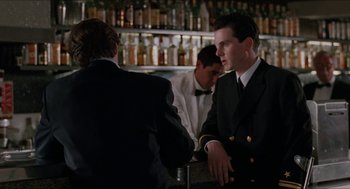 Movie still from “Barcelona” (1994), directed by Whit Stillman – A man in a suit is talking to another man in a suit; Medium shot, Over the shoulder angle