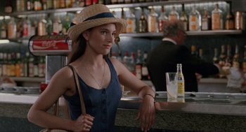 Movie still from “Barcelona” (1994), directed by Whit Stillman – A woman wearing a straw hat sitting at a bar; Medium shot, Over the shoulder angle
