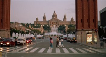 Movie still from “Barcelona” (1994), directed by Whit Stillman – People crossing a street in front of a large building; Extreme Wide shot, High angle