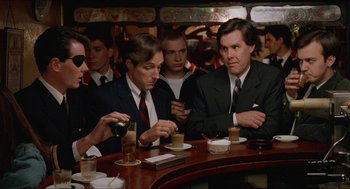 Movie still from “Barcelona” (1994), directed by Whit Stillman – A group of men sitting at a table in a restaurant; Medium shot, Over the shoulder angle